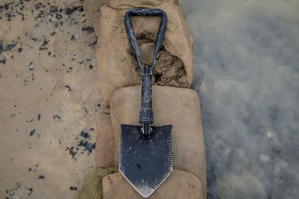 Folding survival shovel with serrated edges